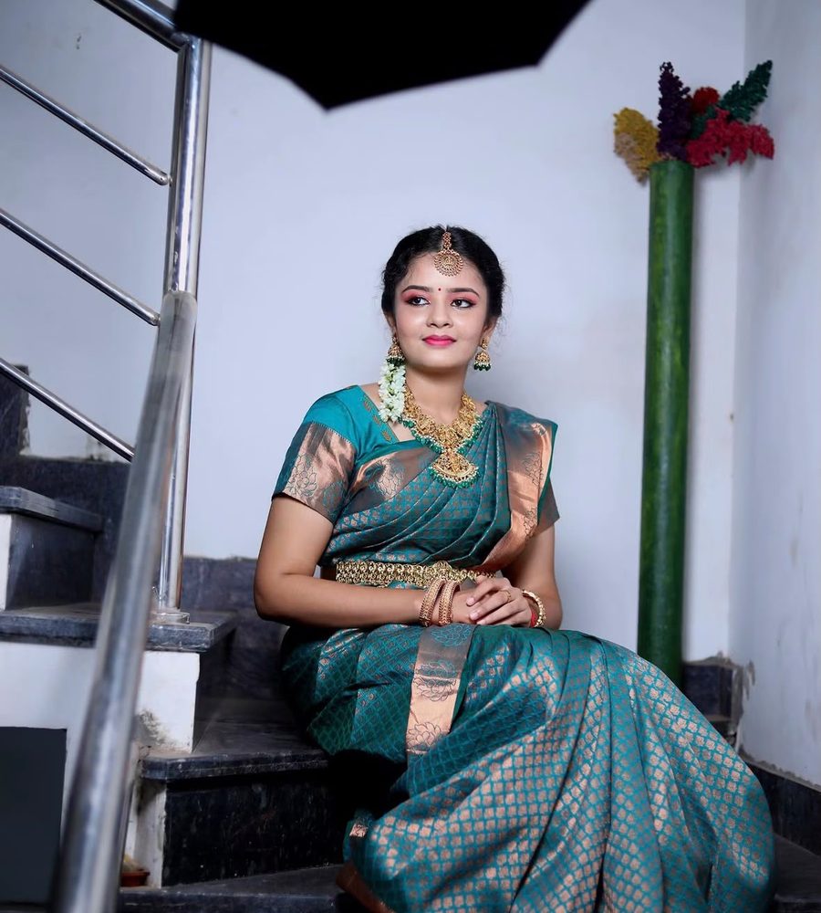 Bride in teal silk saree seated on a staircase